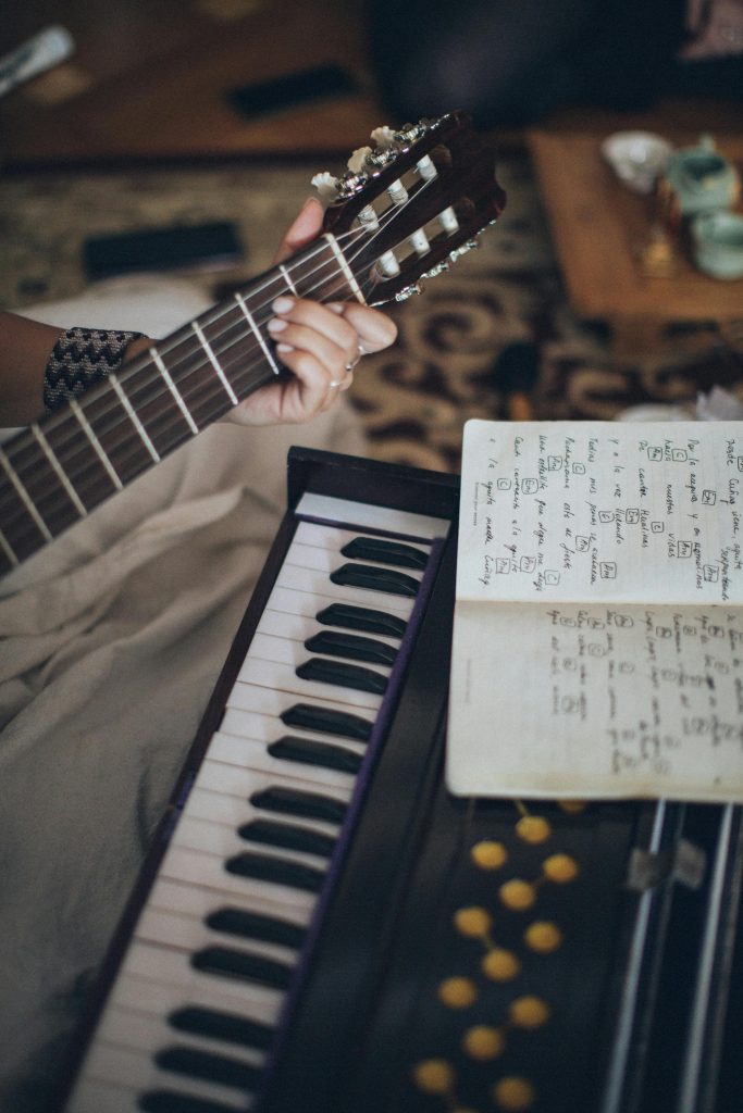 Close-up view of a guitar and keyboard with sheet music, capturing a cozy indoor music session.
